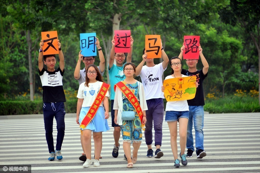 商学院暑期社会实践大学生志愿者在聊城市街头,手举文明过马路标语,在